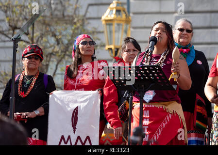 San Francisco, USA. 19. Januar, 2019. Der Frauen März San Francisco beginnt mit einer Kundgebung am Civic Center Plaza vor der City Hall. Fehlende und ermordeten indigenen Frauen war ein prominenter Thema im März und Rallye. Eine Gruppe von Indianischen Frauen in rot gekleidet gesammelt, die Rallye begann und auch marschierten die Aufmerksamkeit auf das Problem in Nordkalifornien zu bringen. Hier wird die arist, Autor und Aktivist Kanyon Sayers-Roods die Rallye mit einem Song wird geöffnet. Sayers-Roods ist von Costanoan Ohlone und Chumasch Erbe, und ihre Arbeit hat im De Young Museum und der Somarts Galerie gekennzeichnet worden. Gutschrift: Stockfoto