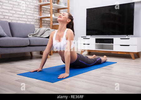 Schöne junge Frau liegend auf Trainingsmatte zu tun Training zu Hause Stockfoto