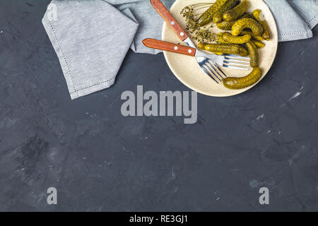 Eingelegte Gurken oder Gurken in der Platte auf der Rückseite Betonoberfläche Tabelle von oben. Platz kopieren, Ansicht von oben, freier Platz für Ihren Text. Stockfoto