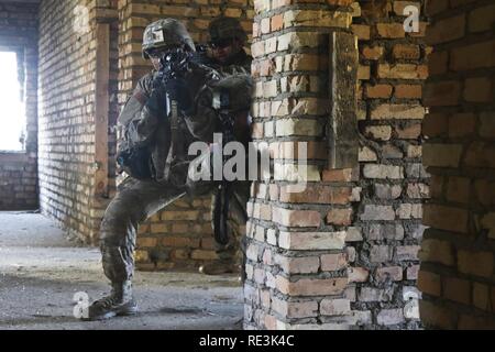 Us-Armee SPC. Tamaricus Tanner (Mitte), infanterist, zusammen mit anderen Fallschirmjäger des 3.platoon, das Unternehmen D, 2.BATAILLON, 503Rd Infanterie Regiment, 173Rd Airborne Brigade zugeordnet, aus der unteren Etage eines verlassenen Gebäude während eines bi-laterale Schulungsveranstaltung mit dem Polnischen 6 Airborne Bataillon, 16 Airborne Brigade (nicht dargestellt), der in einem städtischen Operations Training Facility in Wedrzyn, Polen, Nov. 21, 2016. Ein Teil der Mission in ganz Osteuropa für die 173Rd Abn. Bde. ist zu helfen, das NATO-Bündnis zu stärken. Dies ist zum Teil durch die Verbesserung der leichten Infanterie Alliierten tactica getan Stockfoto