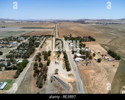 Luftaufnahme einer ländlichen Landschaft mit einer geraden Straße, die landwirtschaftliche Felder unter klarem Himmel trennt Stockfoto