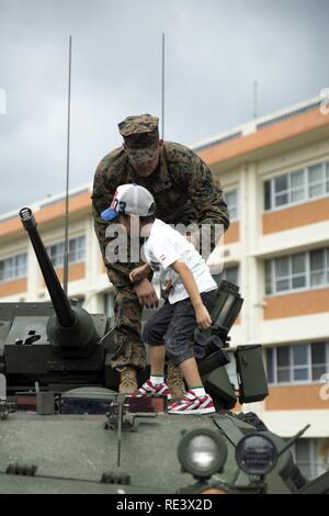 Sgt. Daniel Vreeland hilft einem Kind klettern Sie auf die Oberseite eines leichten gepanzerten Fahrzeug 07.11.20 Während der Japan Masse Verteidigung-kraft Festival auf Lager Naha, Okinawa, Japan. Das Festival feierte der 6. Jahrestag des 15 Brigade und der 44. Jahrestag des Camp Naha. Daniel, ein Santa Clarita, Kalifornien, Eingeborener, ist ein LAV crewman mit Combat Assault Bataillon, 1st Marine Division, III Marine Expeditionary Force. Stockfoto