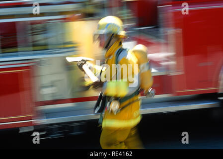 Ein Feuerwehrmann in voller Weide trägt eine Axt an einer Feuerstelle, USA 1993 Stockfoto