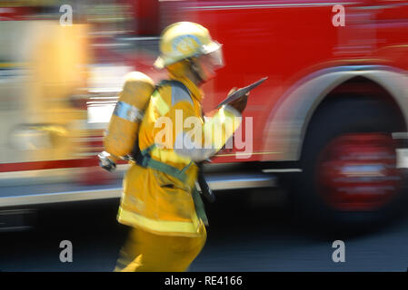 Ein Feuerwehrmann in voller Weide trägt eine Axt an einer Feuerstelle, USA 1993 Stockfoto