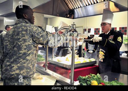 1 st. Sgt. Daniel Salinas der 226th Signal Unternehmen dient, eine Scheibe von der Türkei in einen 10 Mountain Division Sustainment Brigade Soldaten während der Brigade Thanksgiving Feier im Speisesaal November 22. Führungskräfte aus jedes Bataillon und Firma serviert den hungrigen Soldaten als Teil der Thanksgiving Feier. Stockfoto
