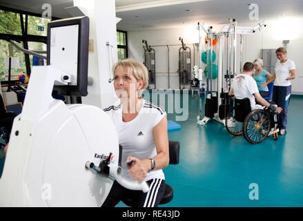 Patienten, die in den Muskeln Training auf verschiedenen Maschinen in einer Turnhalle, Physiotherapie, Physikalische Therapie in einer neurologischen Stockfoto