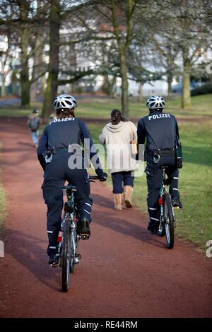 Fahrrad Polizei patrouilliert in einen städtischen Park Stockfoto