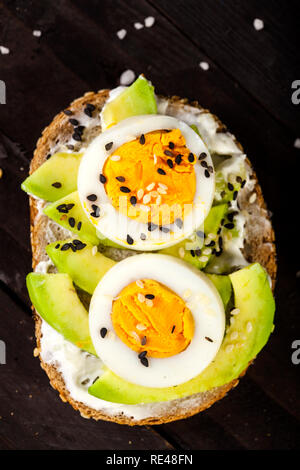 Nahaufnahme von Bruschetta mit Avocado, Käse, Ei, auf einen hölzernen Tisch Sesam. Stockfoto