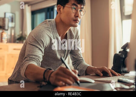 Fotograf mit einem Tablet und Stylus Photo bearbeiten in seinem Studio zu tun. Konzentriert Photo Editor arbeiten in seinem Atelier. Stockfoto