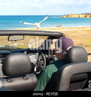 Mann sitzt in einem Auto beobachten die Strand Stockfoto