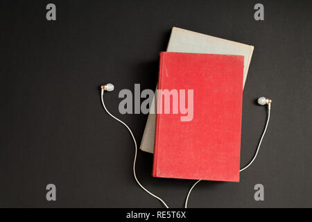 Hörbuch Konzept. Kopfhörer und Buch über schwarzen Tisch Hintergrund. Ansicht von oben mit Platz für Ihren Text Stockfoto