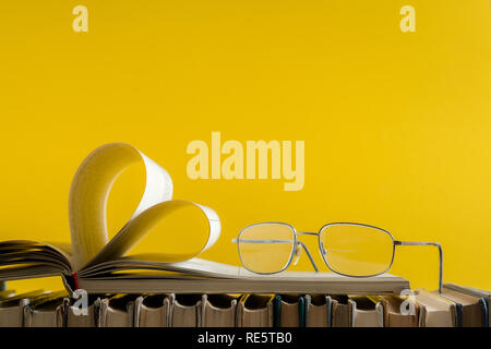 Alte hard cover Buch Seite schmücken Herzform mit Brille auf der Seite für die Liebe am Valentinstag mit unscharfen Hintergrund und kopieren Sie Platz für Text. C Stockfoto