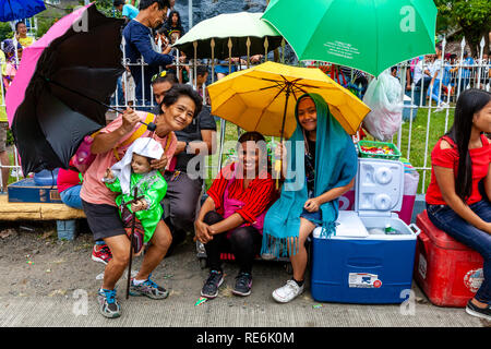 Kalibo, auf den Philippinen. 20. Januar 2019. Eine Gruppe philippinischer Straßenhändler mit einem religiösen Symbol warten für Menschen, die an der Hauptstraße Prozession zu Ehren Santo Nino (Heiligen Kind) am letzten Tag des jährlichen Ati-Atihan-Festival in der Stadt von Kalibo, Panay Island, Philippinen. Credit: Grant Rooney/Alamy leben Nachrichten Stockfoto