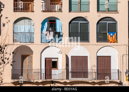 Fassade eines Hauses in der Gemeinde Bagà mit stelada Flagge auf einem Balkon und einer Frau auf einer anderen, Bagà, Katalonien, Spanien Stockfoto