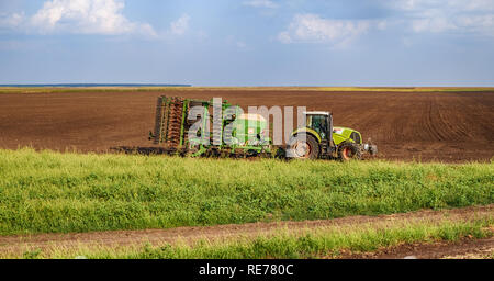 Giurgiu, Rumänien - August 29, 2018. Landwirtschaft grünen Traktor säen und pflegen Feld am späten Nachmittag Stockfoto