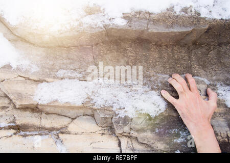 Die Hand eines Mannes klammert sich an einer Leiste auf einen Stein. Stockfoto