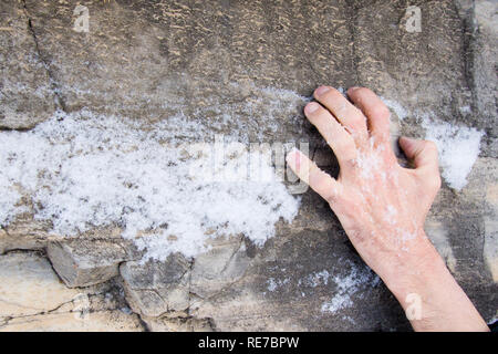 Die Hand eines Mannes klammert sich an einer Leiste auf einen Stein. Stockfoto