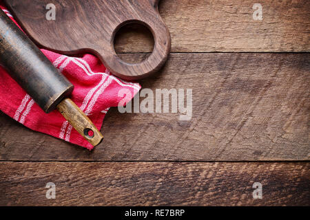 Holz Nussbaum Schneidbrett und vintage Rolling Pin über den roten Küchentuch und rustikale alte Scheune Holz Tisch. Bild geschossen von oben in der Ansicht von oben. Stockfoto