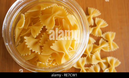 Nudeln in Form von Bögen aus Glas Glas verstreut. Italienische Pasta Stockfoto