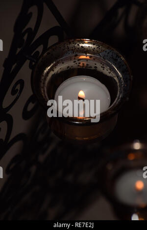 Kerze Teelichter als Weihnachten Hintergrund mit bokeh Effect, hell brennenden Teelicht Kerzen in einem goldenen - farbige Leuchter für Meditation und rel Stockfoto