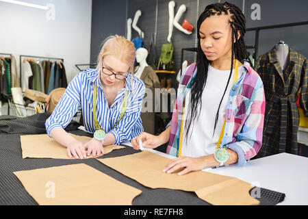 Zwei junge Modedesigner Skizzen auf Stoff zusammen bei Schneider Tabelle in der Werkstatt Stockfoto