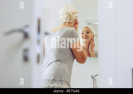 Schöne positive ältere Frau ihre Wange berühren Stockfoto