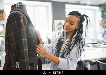 Young Fashion Designer mit afrikanischen Zöpfe auf schaufensterpuppe stehend in ihrer Werkstatt Stockfoto