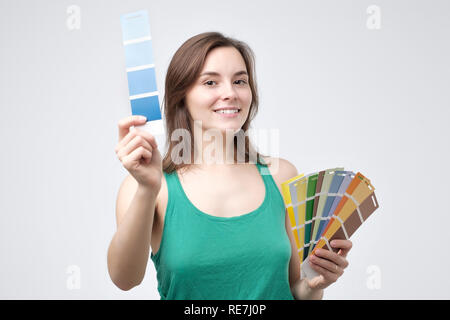 Junge europäische Frau in grün Kleidung wählen Sie eine Farbe Ihrer Wand zu malen Stockfoto