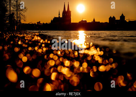 Sonne geht neben dem Kölner Dom unter Sterben. Im Vordergrund reflektiert das Wasser des Rheins. Stockfoto