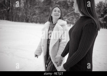 Zwei Mädchen halten Sie Hände und durch den Winter Wald. Schwarz-weiß-Bild. Stockfoto