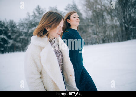 Zwei Mädchen gehen durch den Winter schneebedeckten Wald. Stockfoto