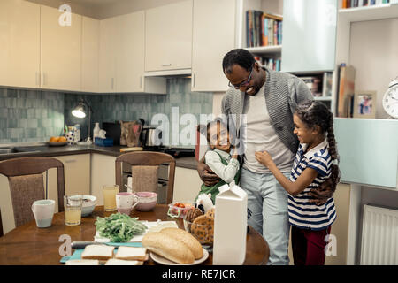 Süße Zwillinge Gefühl schöne und gleichzeitig Vater in der Küche Stockfoto