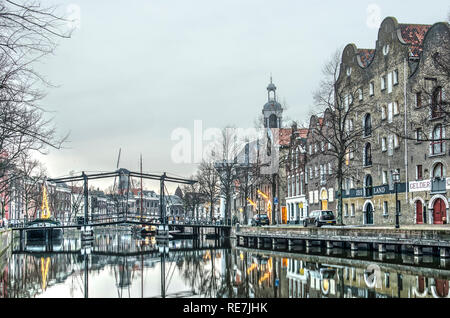 Schiedam, Niederlande, 27. Dezember 2018: Boote, eine Fußgängerbrücke, die grachtenhäuser, Lagerhäuser, eine Windmühle und den Hafen Kirche spiegeln sich in der w Stockfoto