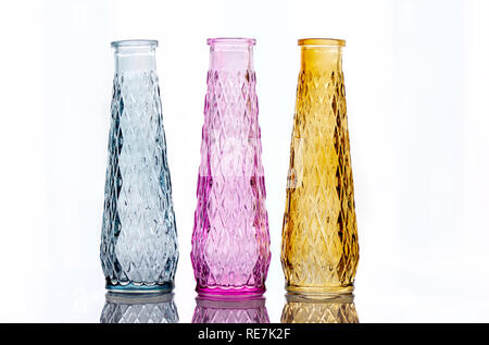 Drei Vasen aus farbigem Glas mit einem Muster, auf hellem Hintergrund mit Reflexion isoliert. Stockfoto