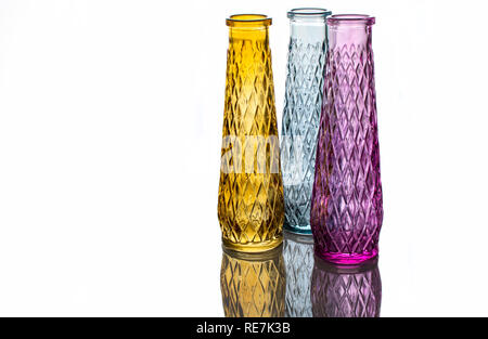 Drei Vasen aus farbigem Glas mit einem Muster, auf hellem Hintergrund mit Reflexion isoliert. Stockfoto