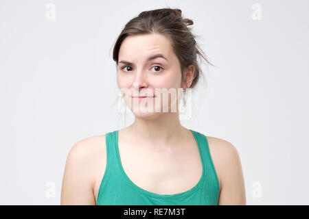 Zweifelnde Frau enttäuscht oder über graue Wand unbeeindruckt. Stockfoto