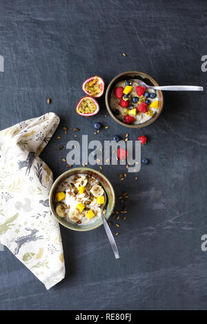 Ein gesundes Frühstück. Porridge mit Banane, Blaubeeren, Himbeeren, Passionsfrucht, Mango und Samen. Stockfoto