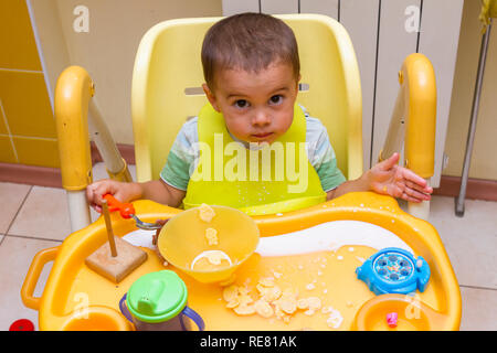 Kind Junge lernt, die Tabelle, in der die Kinder in der Küche zu essen. Baby isst, lustig. Little Baby isst mit einem Löffel Suppe Platte. Er sitzt auf einem CHILDRE Stockfoto