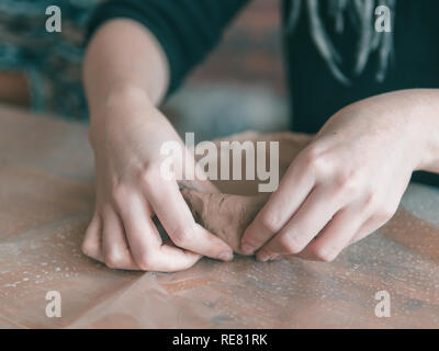 Weibliche Keramiker Hände machen trendige Platte von braun Ton. Nahaufnahme der Finger gemacht Mode Dessert flache Platte für das Handwerk Werkstatt. Stockfoto