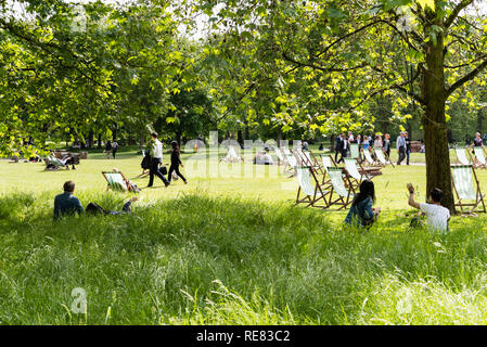 Junge Paare, die Relaxen im Green Park, London an einem Sommertag. Stockfoto