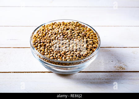 Roh Linsen in eine Glasschüssel auf Schwarz Stein Hintergrund. Gesunde vegetarische Essen Konzept. Superfoods. Kopieren Sie Platz. Linsen sind reich an komplexen carbohydra Stockfoto
