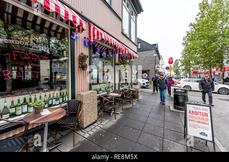 Reykjavik, Island - 19. Juni 2018: Nasse Straße Straße gepflasterten Gehweg in der Innenstadt von Center und Zeichen für Fondue farbenfrohe Restaurant Cafe und Menschen w Stockfoto