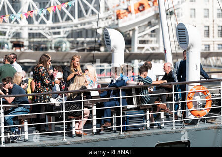 London, UK, 21. Juni 2018: Viele Touristen in Boot Schiff auf der Themse sitzen im Blick auf London Eye in Restaurant Cafe Pub suchen Stockfoto