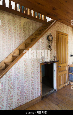 Kiefernholztreppe und Wohnzimmer mit Blumentapete in einem alten Haus im Stil der 1807 Jahre. Stockfoto