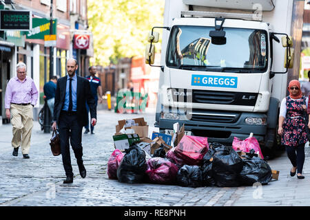 London, Großbritannien, 22. Juni 2018: die Menschen zu Fuß pendeln auf der Straße von vielen Plastikabfallbeutel auf der Straße bei Lieferwagen und Greggs Zeichen, Geschäftsmann Wal Stockfoto