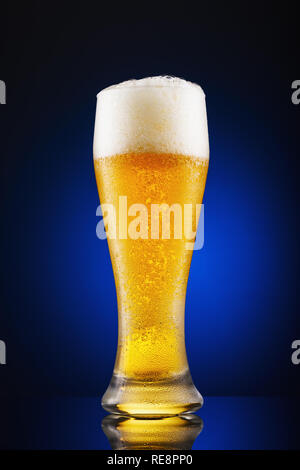 Glas frisch gezapftes Bier auf einem blauen Hintergrund Stockfoto