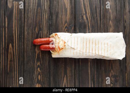 Ausschreibung Wurst in pita Brot auf hölzernen Hintergrund. Foto mit Kopie Raum Stockfoto