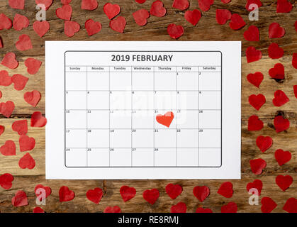 Konzeptionelle Bild von 2019 Februar Kalender und Gegenwart Geschenk mit roter Schleife auf rustikalen vintage Tabelle in sich bereit für Saint Valentines Tag gewickelt Stockfoto