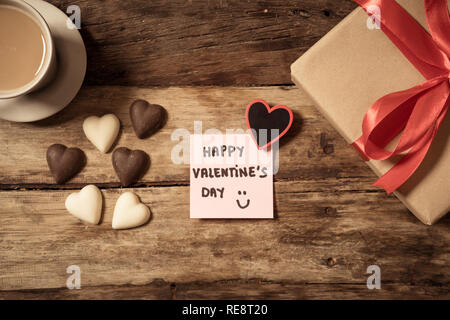 Schöne Ansicht von oben Valentines Zusammensetzung von Geschenk, Schokolade in Herzform, Kaffee und Happy Valentines Tag Hinweis auf Post-it im Vintage Stil geschrieben wird Stockfoto