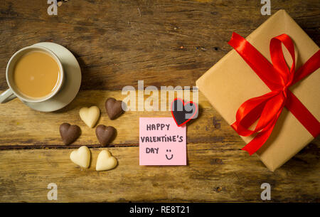 Schöne Ansicht von oben Valentines Zusammensetzung von Geschenk, Schokolade in Herzform, Kaffee und Happy Valentines Tag Hinweis auf Post-it im Vintage Stil geschrieben wird Stockfoto